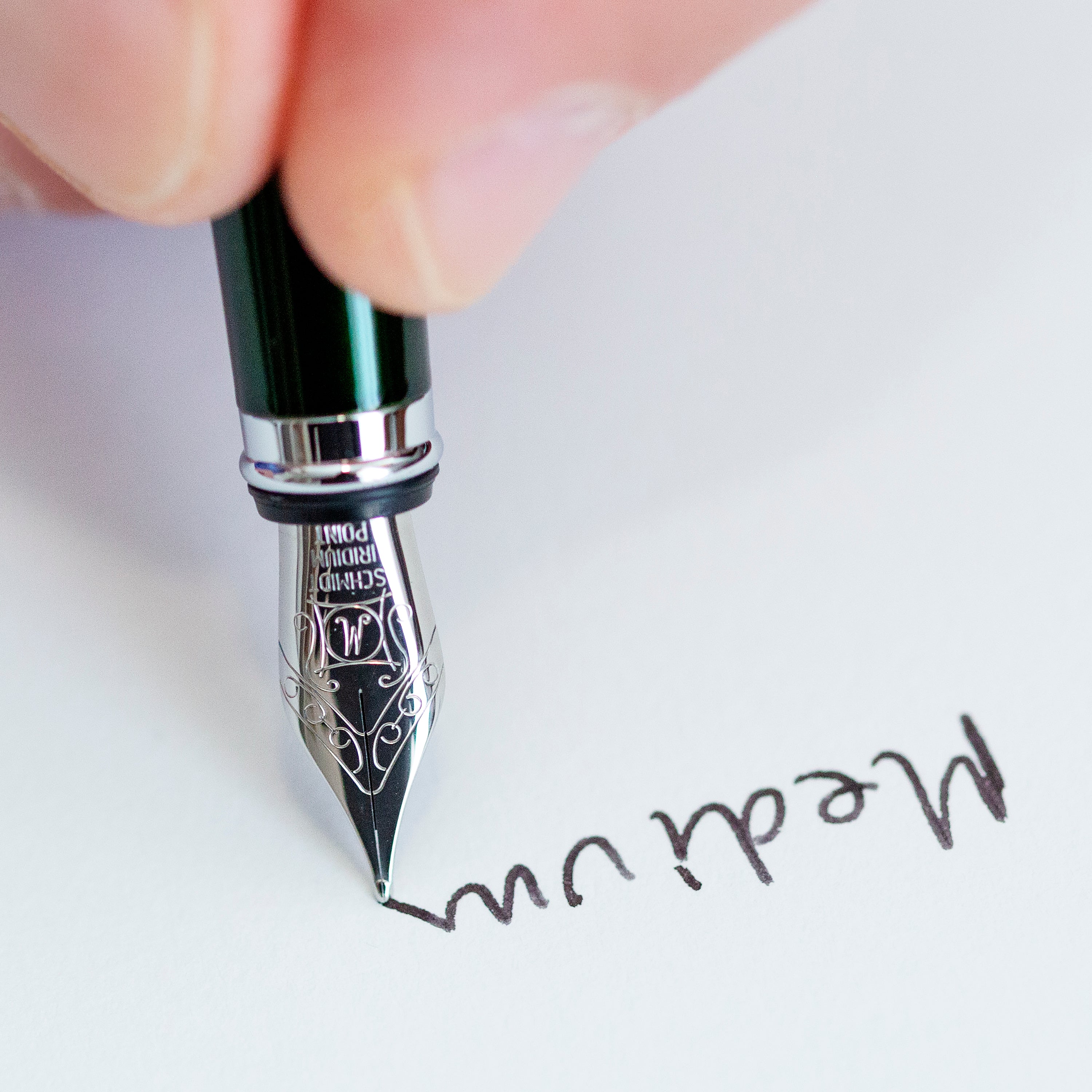 Fountain pen nib writing on paper with a close-up focus on the tip.